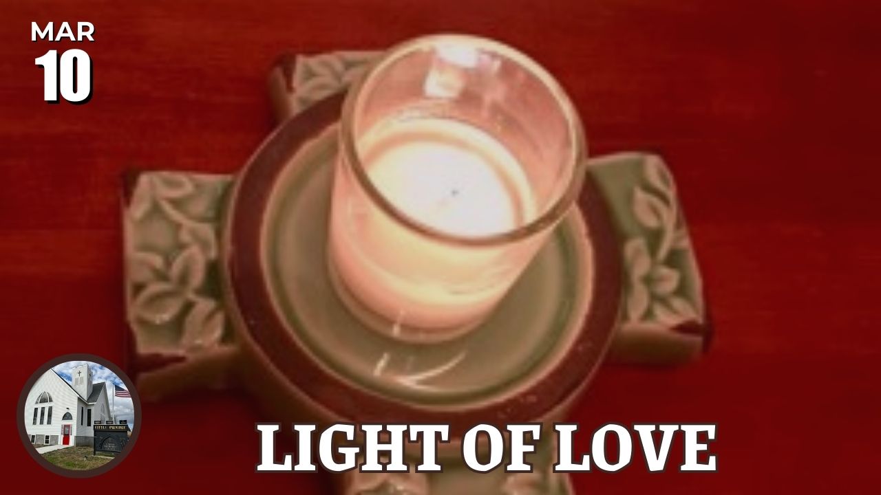 lit candle in votive on cross base